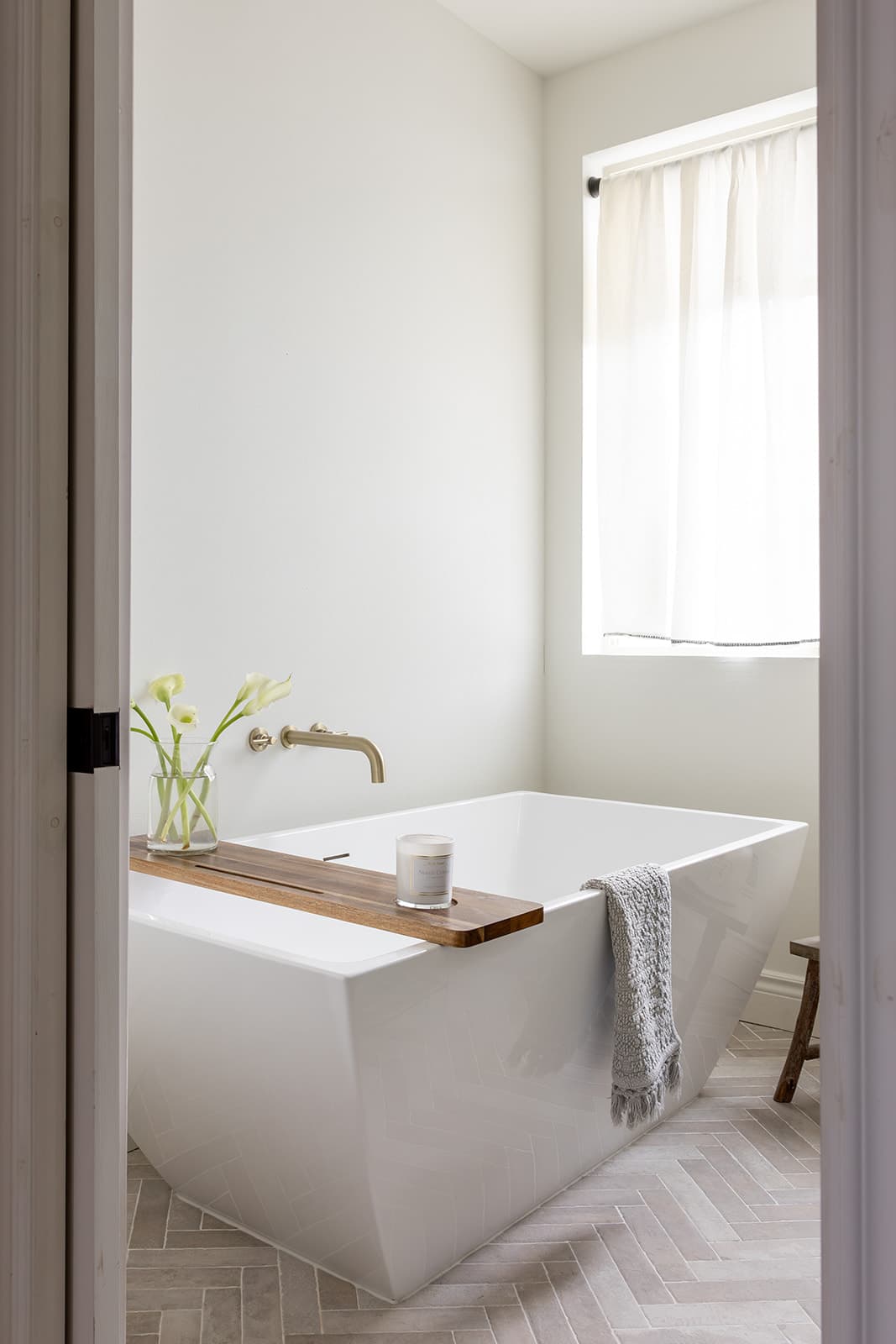 Warm modern bathroom remodel with a wood vanity and herringbone tile floor by Portland Tile in Portland, OR