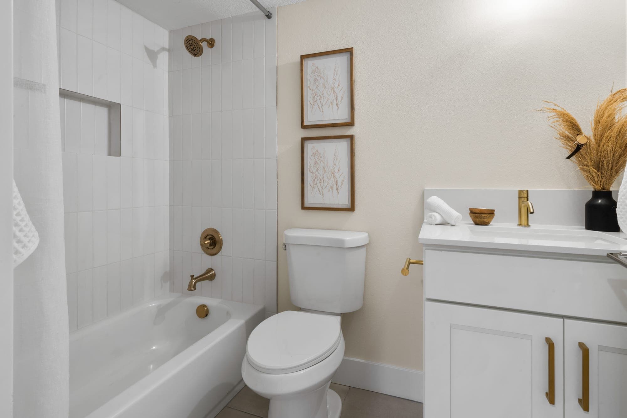 Bathroom with a new tub, white straight set wall tile, a custom niche, gold fixtures, and a quartz vanity in Southwest Portland, OR
