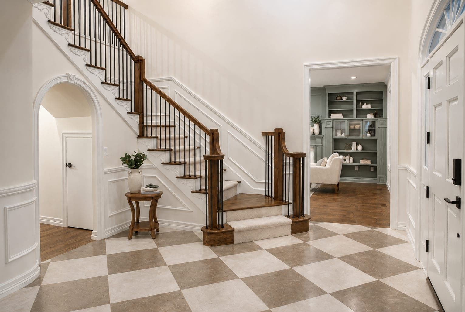 Foyer with a large format checkerboard tile floor, rebuilt staircase with black metal spindles, carpet runner, white wainscot, and an archway in Beaverton, OR