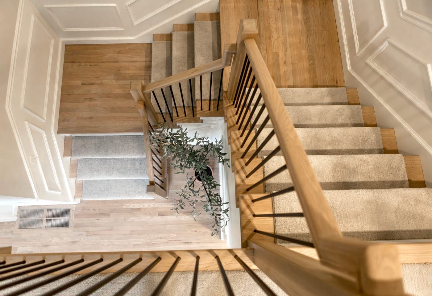 Overhead view of custom hardwood stairs with a carpet runner, a custom wood railing with black metal spindles, and a custom hardwood floor vent by Portland Tile & Remodels