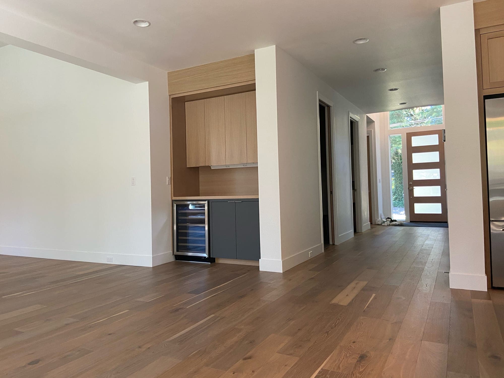 Wide plank flooring running through an open living area toward the entry of a newly finished home by Portland Tile & Remodels