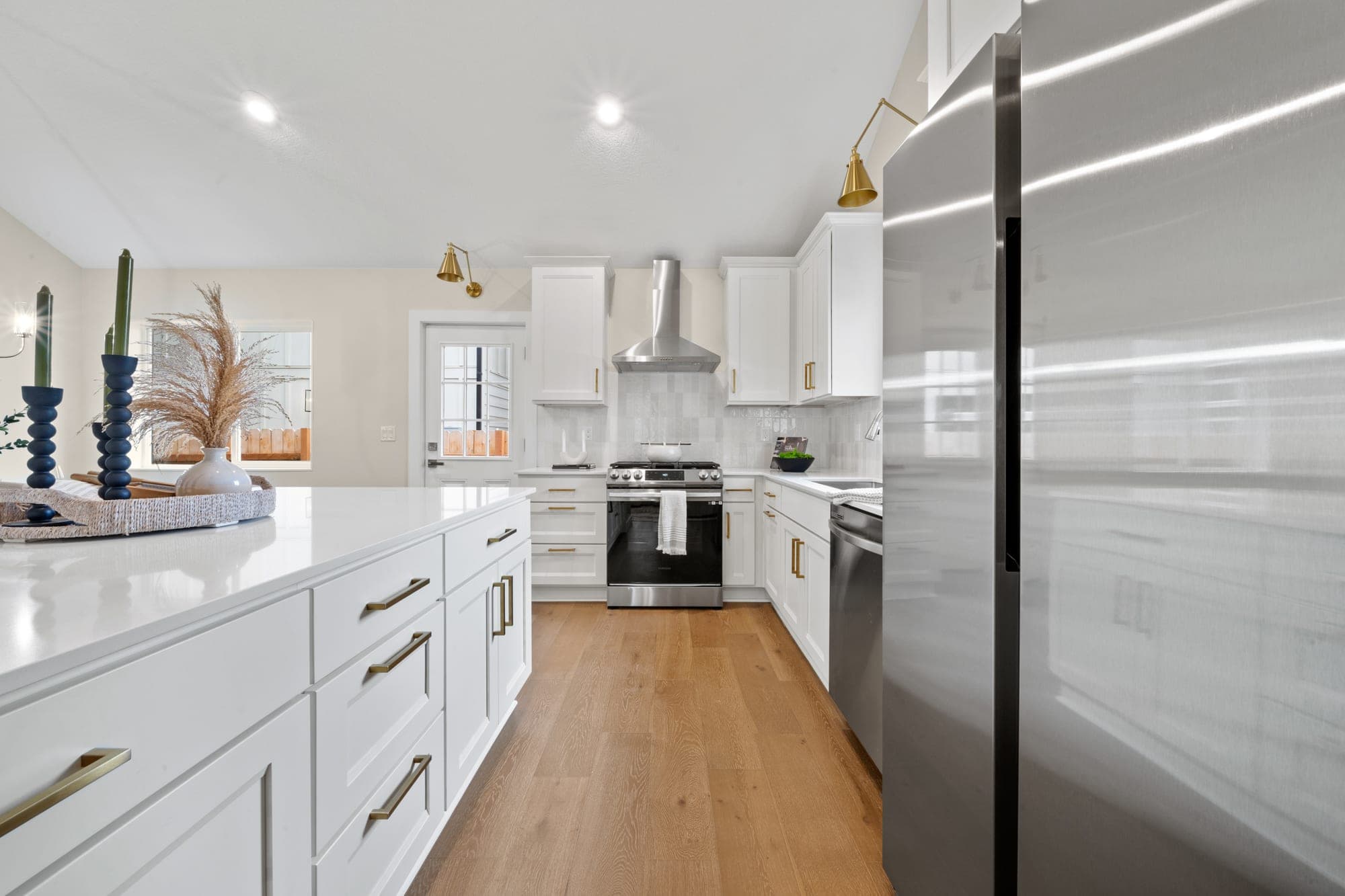 Remodeled kitchen with a large island, white shaker cabinetry, quartz counters, gold hardware, stainless steel appliances, and a cloe tile backsplash in Southwest Portland, OR