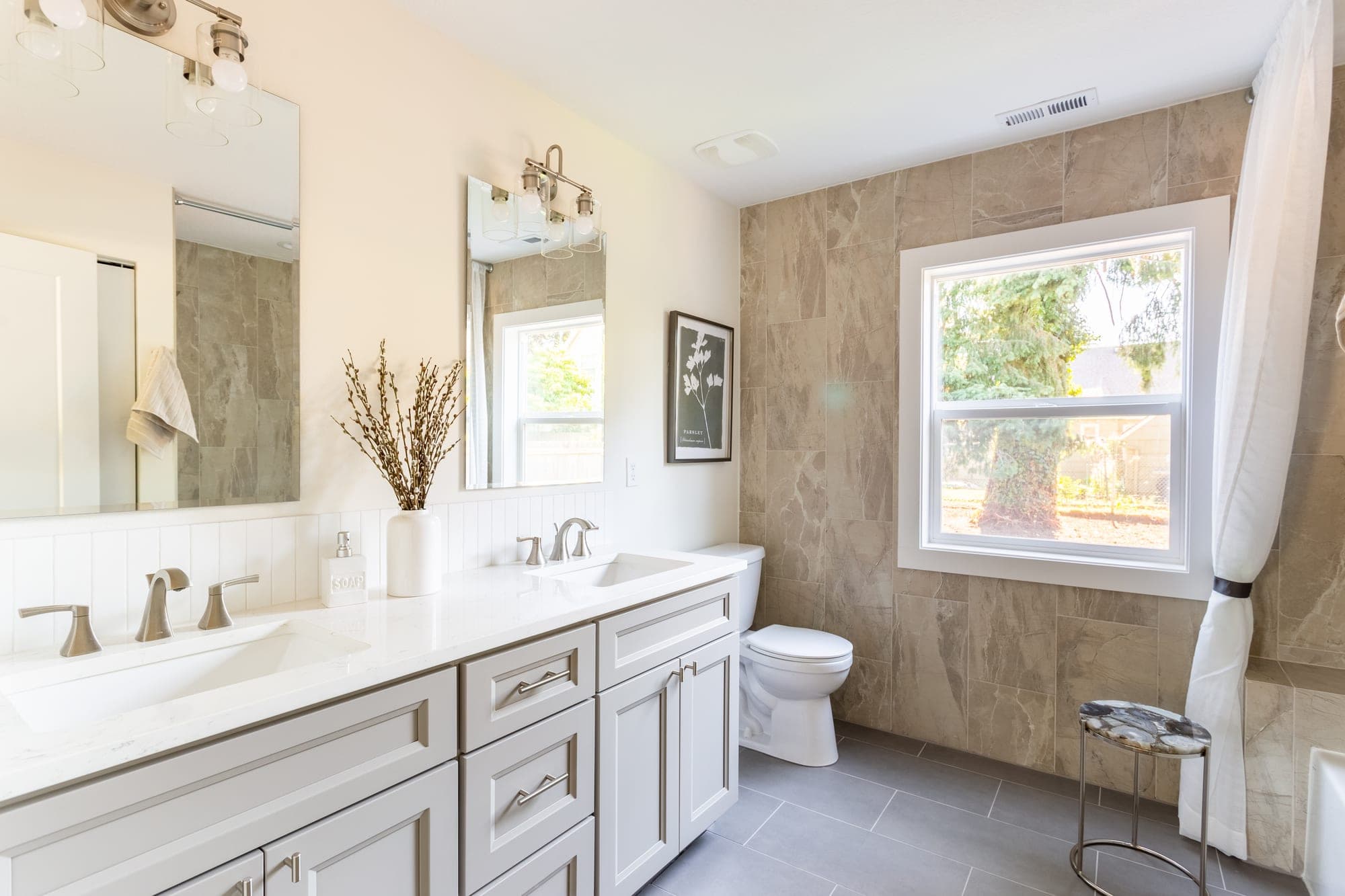 Bathroom with a large format tile feature wall wrapping a window, a quartz topped vanity, and tile flooring in Hillsboro, OR