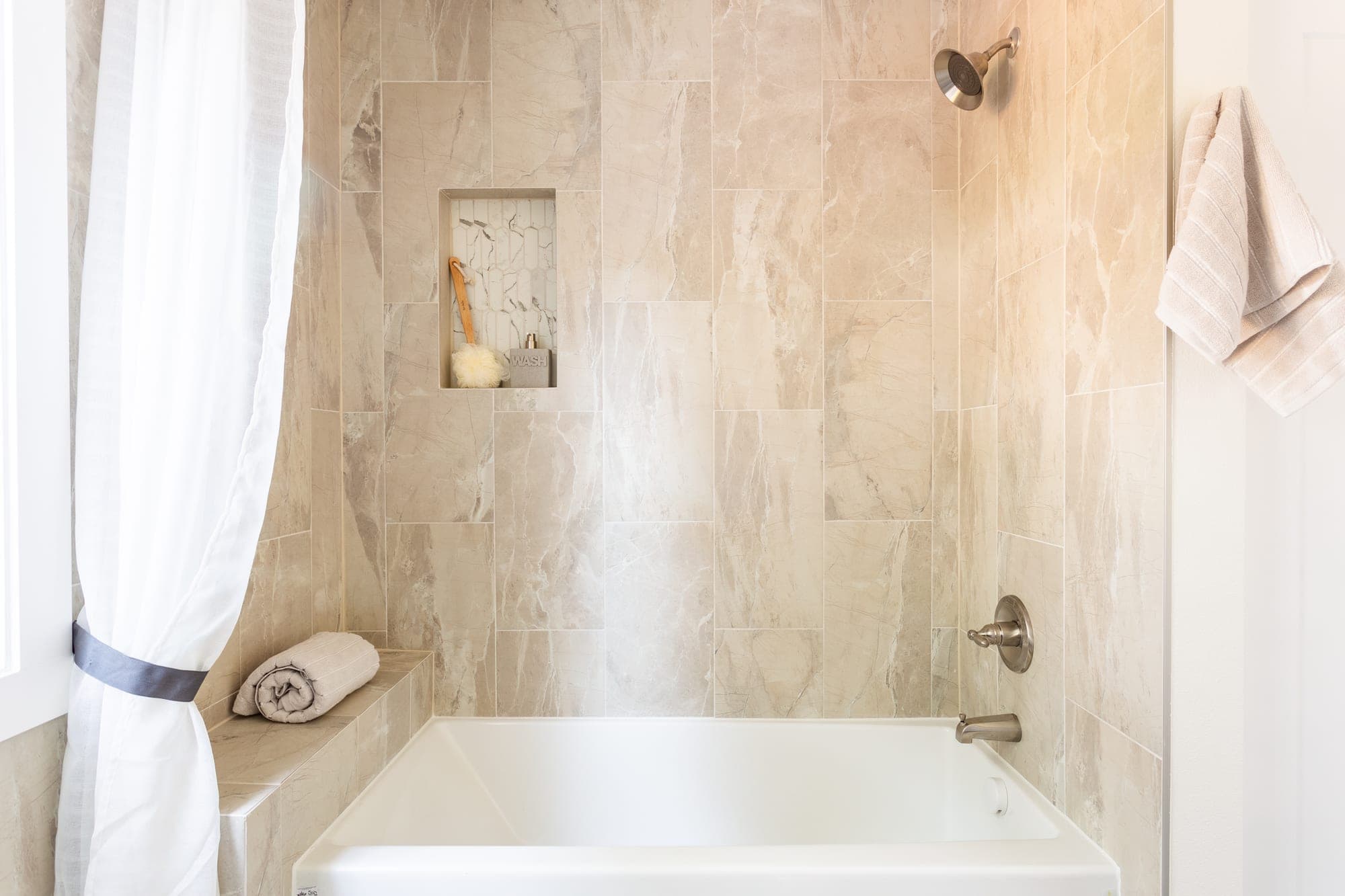 Tub and shower with large format tile walls extending past the tub and a recessed niche finished in hexagon mosaic tile in Hillsboro, OR
