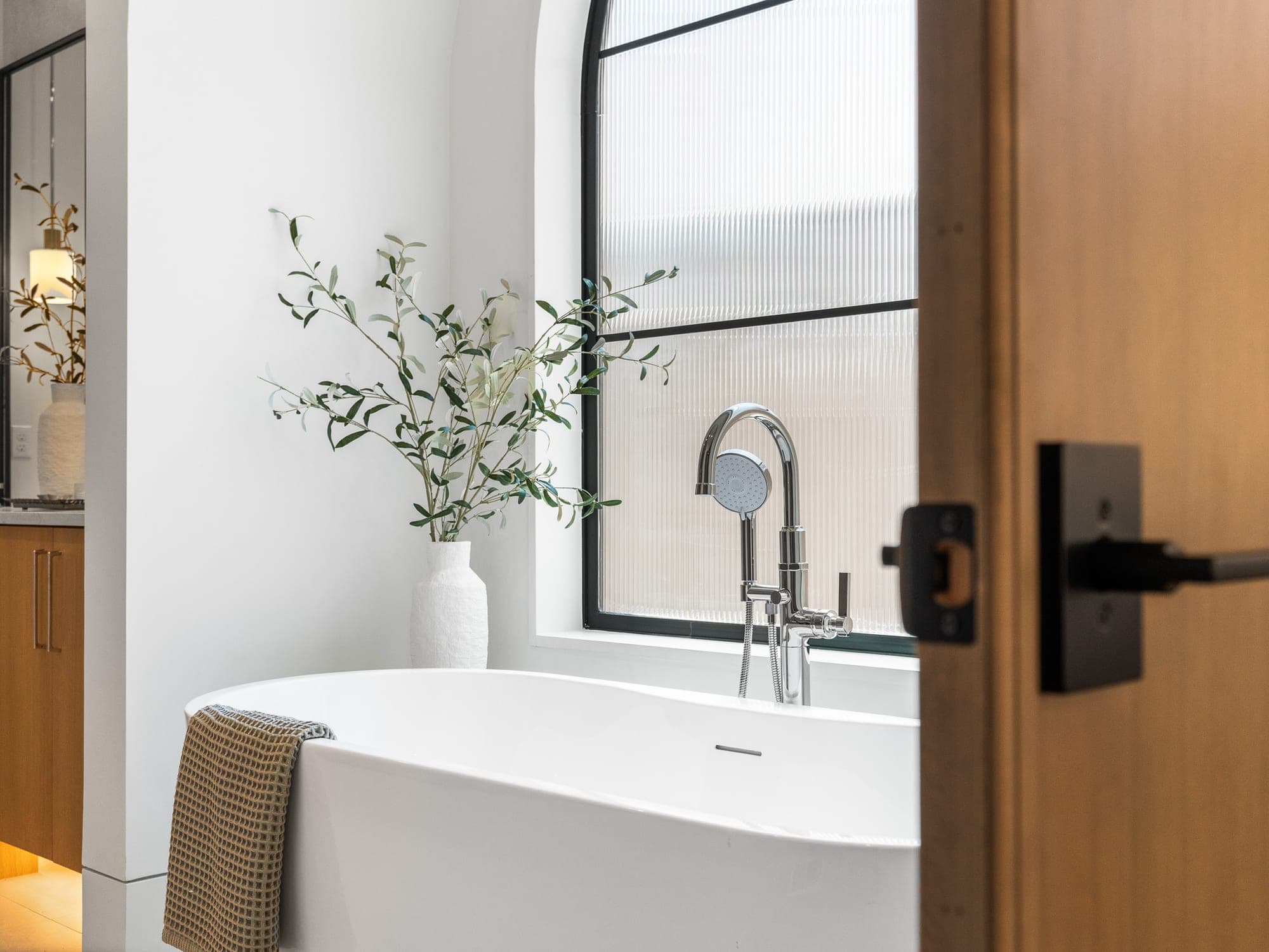 Freestanding tub beside a custom wood vanity with warm under cabinet lighting in Happy Valley, OR