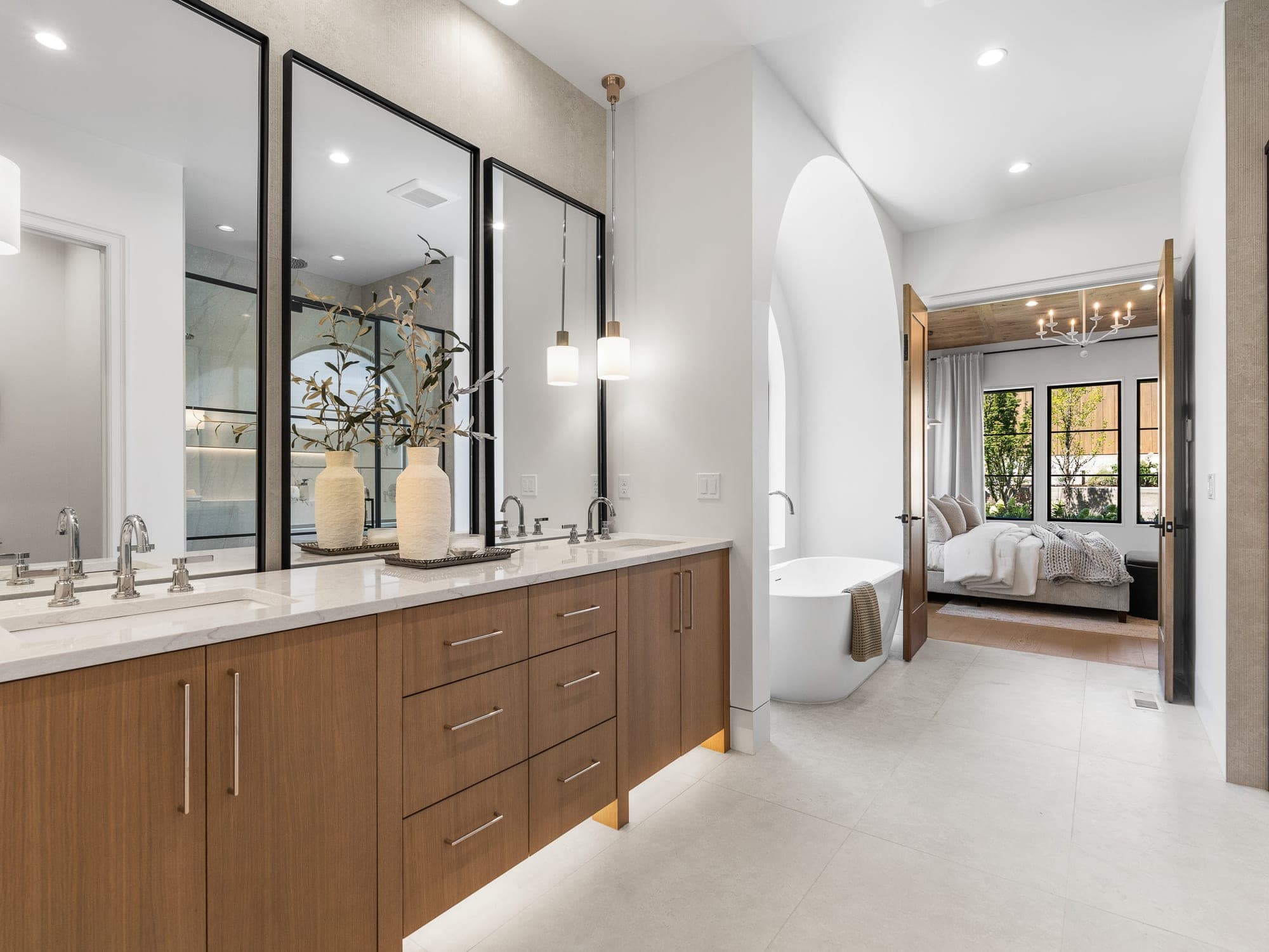 Luxury primary suite with a custom wood vanity, black framed mirrors, pendant lights, and a freestanding tub in Happy Valley, OR