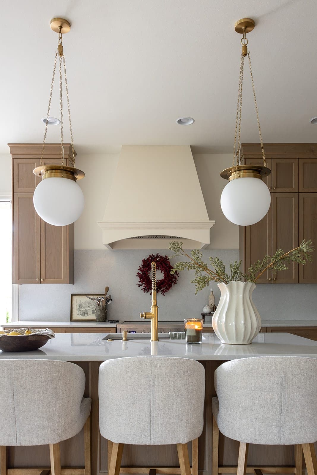 Symmetrical view of two gold globe pendants framing the custom range hood above a quartz island in a white oak kitchen in Camas, WA
