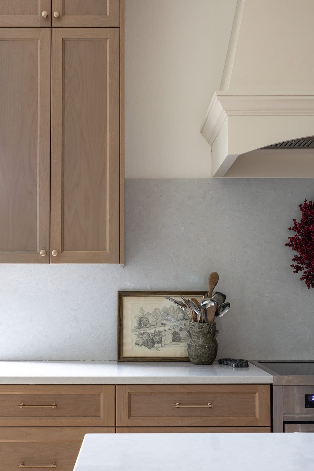 Detail of a full height marbled quartz backsplash meeting white oak cabinetry and the edge of a custom cream range hood in Camas, WA